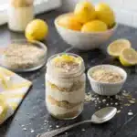 Lemon Cheesecake Overnight Oats in a mason jar on black marble table with lemon zest topping